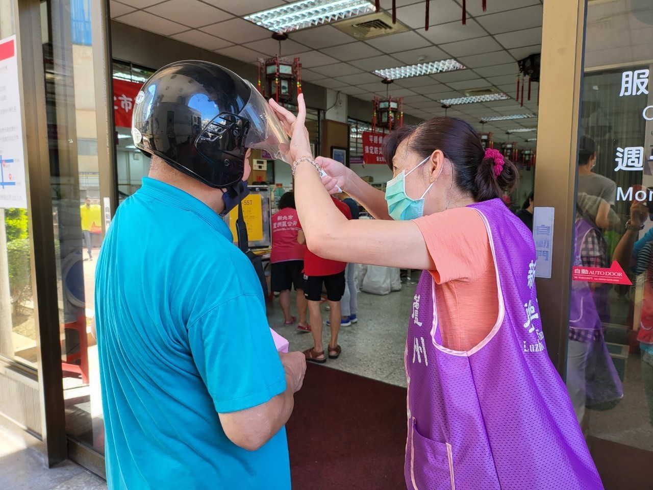 公所志工協助民眾量測體溫及噴酒精